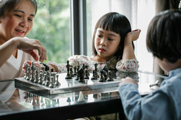Woman teaching two children chess