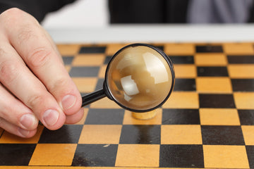 Magnifying glass in front of chess piece, representing chess blindness