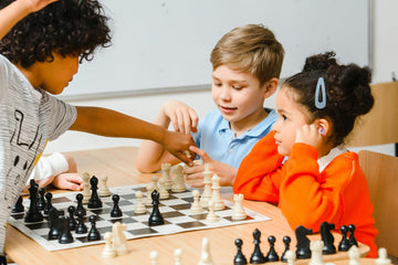 three children playing chess around a table