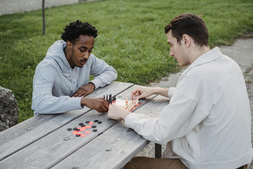 Two men playing outside on a portable chess set