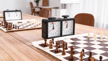 A chess clock next to a chess board on table