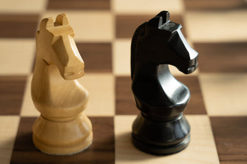 Two Chess knights on a brown and shite chessboard