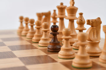 darker pawn among a light wooden chessmen set